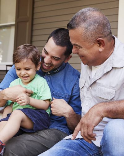 Male Multi Generation Family Sitting On Steps in Front Of House