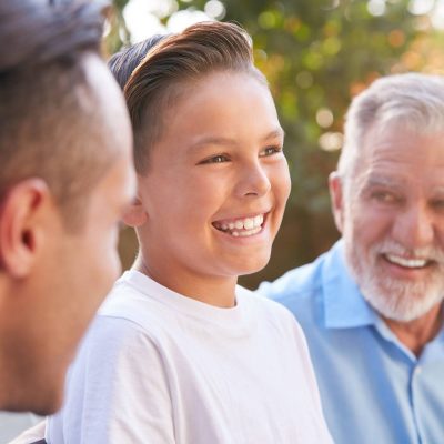 Male Multi-Generation Hispanic Family Relaxing In Garden At Home Together