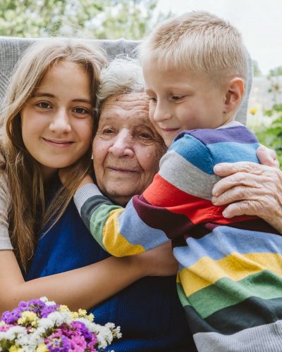 Family groups, multigenerational households, great-grandmother and great-grandchildren. Candid portrait of happy grandmother with grandchildren outdoors.