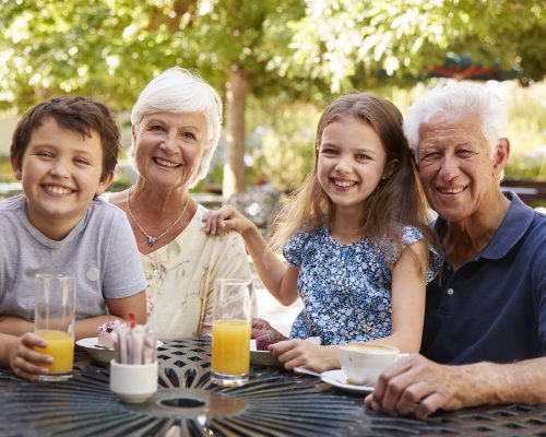 Grandparents And Grandchildren Enjoying Snack At Outdoor Caf