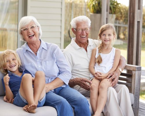 Grandparents With Grandchildren Relaxing On Deck At Home